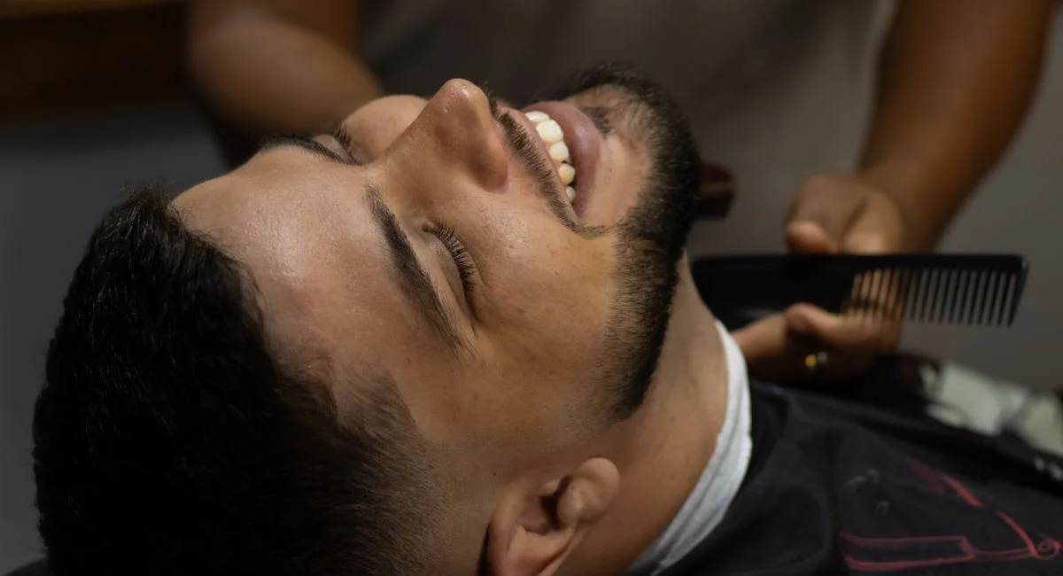 Smiling man receiving a haircut at a barbershop, showcasing a vibrant and relaxed atmosphere.