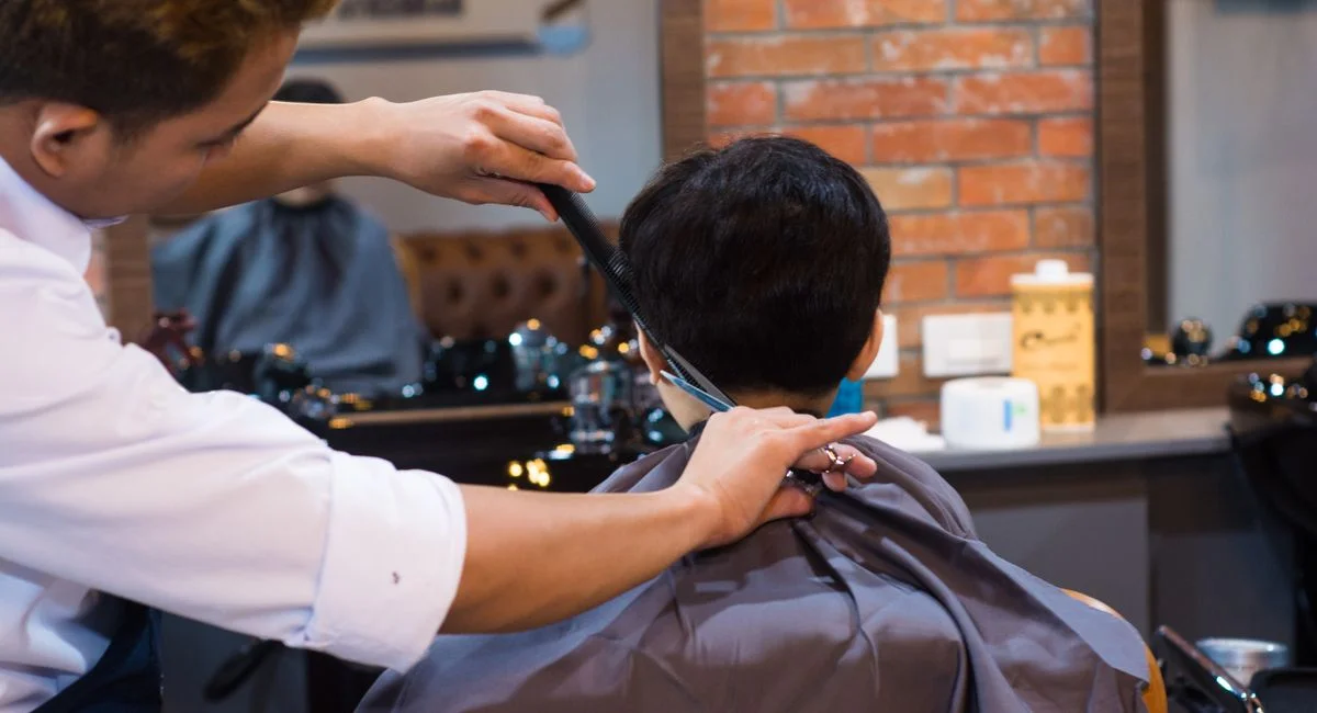 Barber giving a precise haircut to a client in a contemporary barbershop setting.