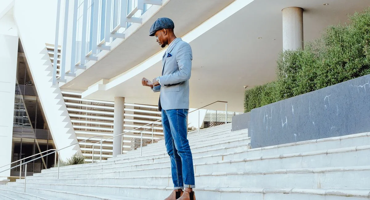 A fashionable man walks confidently on urban steps, showcasing modern architecture.