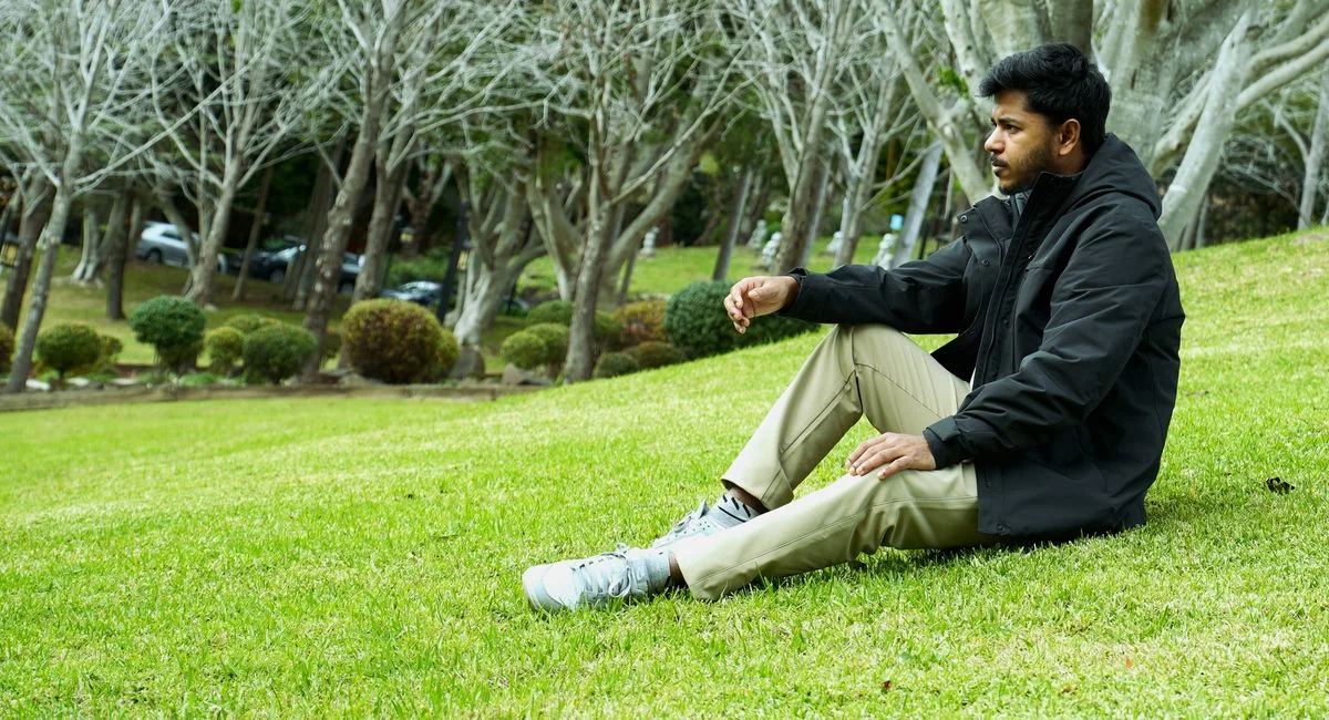 A man sits peacefully in a Wollongong park, surrounded by serene nature and trees.