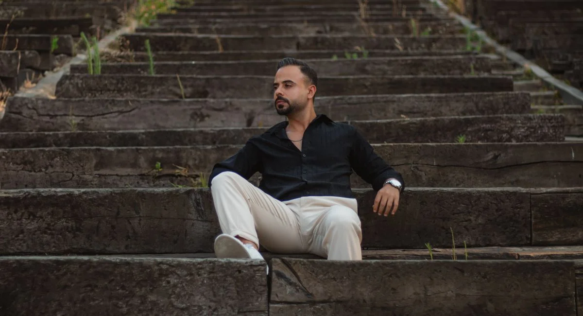 A man sitting on rustic stone steps, dressed in casual attire, enjoying a moment of relaxation.