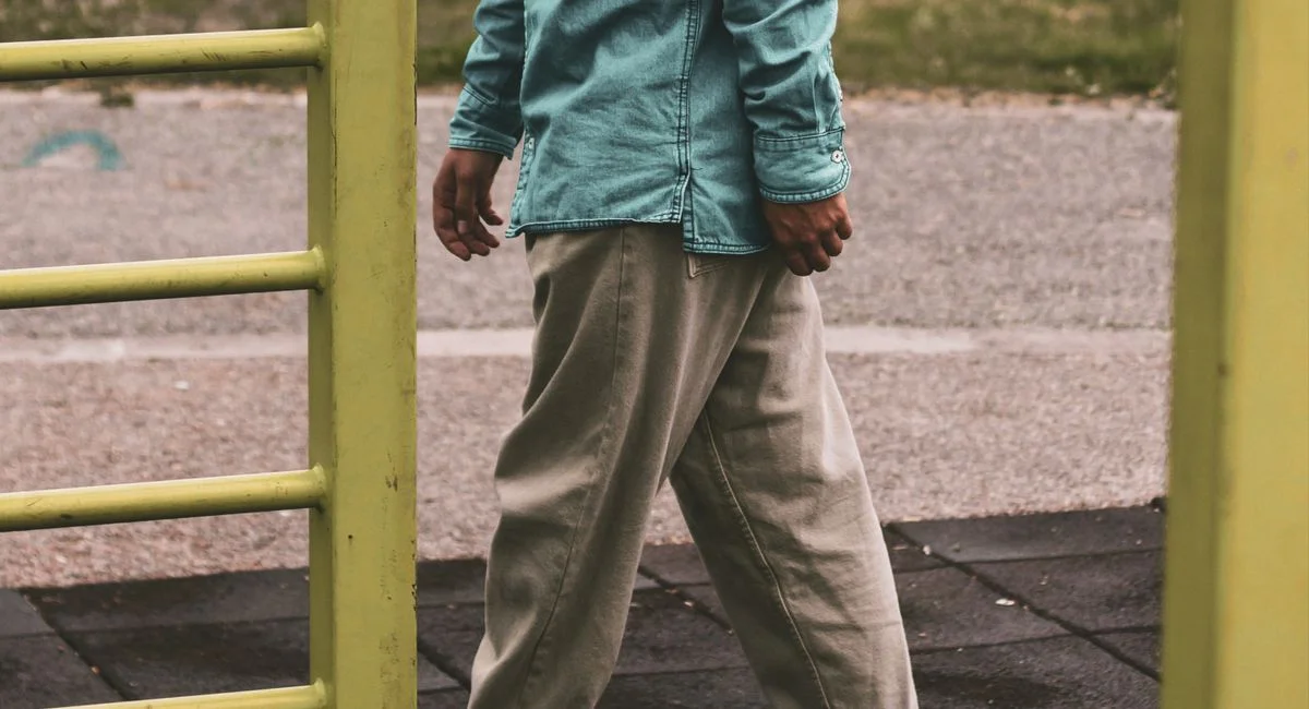 Stylish casual outfit featuring a denim shirt and sneakers in an outdoor setting.