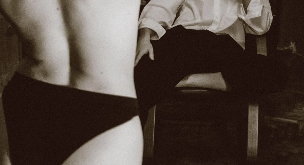 Artistic sepia-toned image capturing intimate moments with playful and erotic elements.