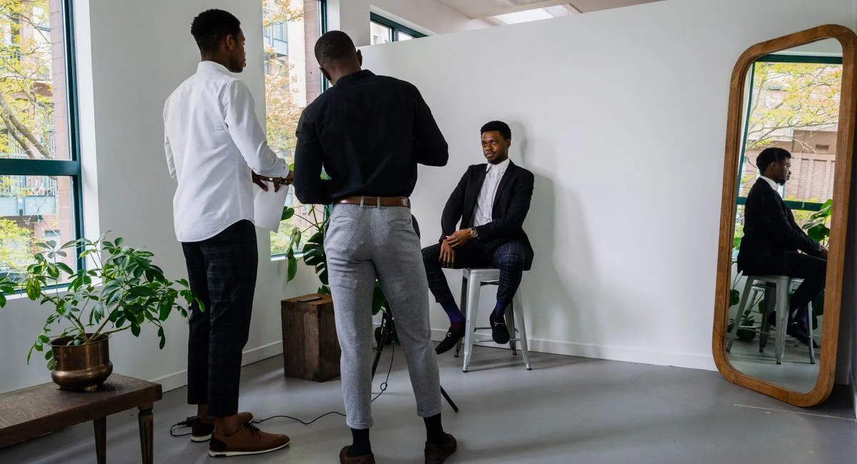 Businessmen preparing a portrait pose with mirror reflections in a modern indoor studio.