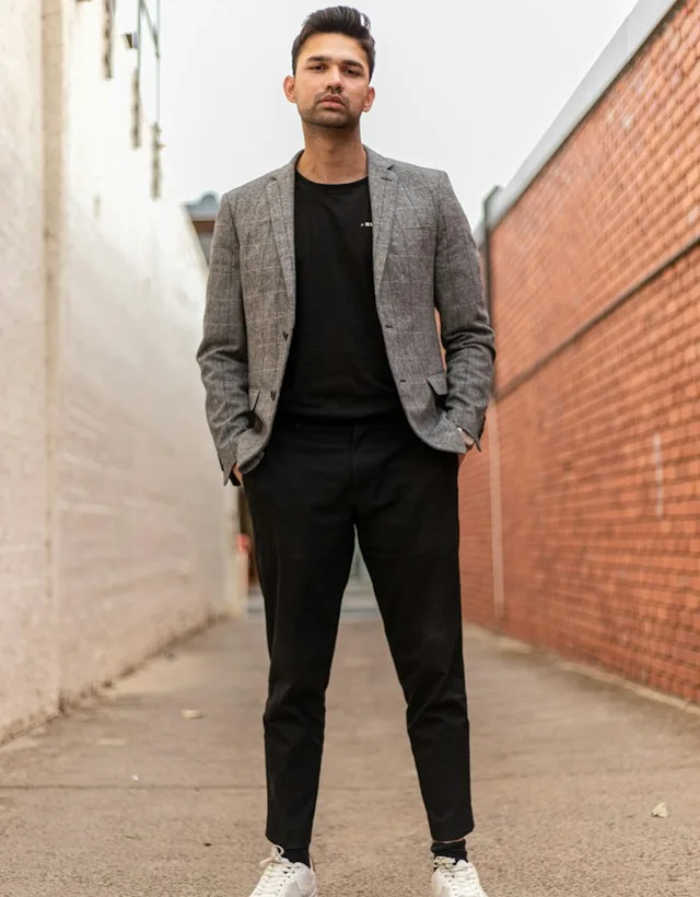 Veste grise à carreaux, haut et pantalon noirs, baskets blanches : silhouette urbaine de démonstration